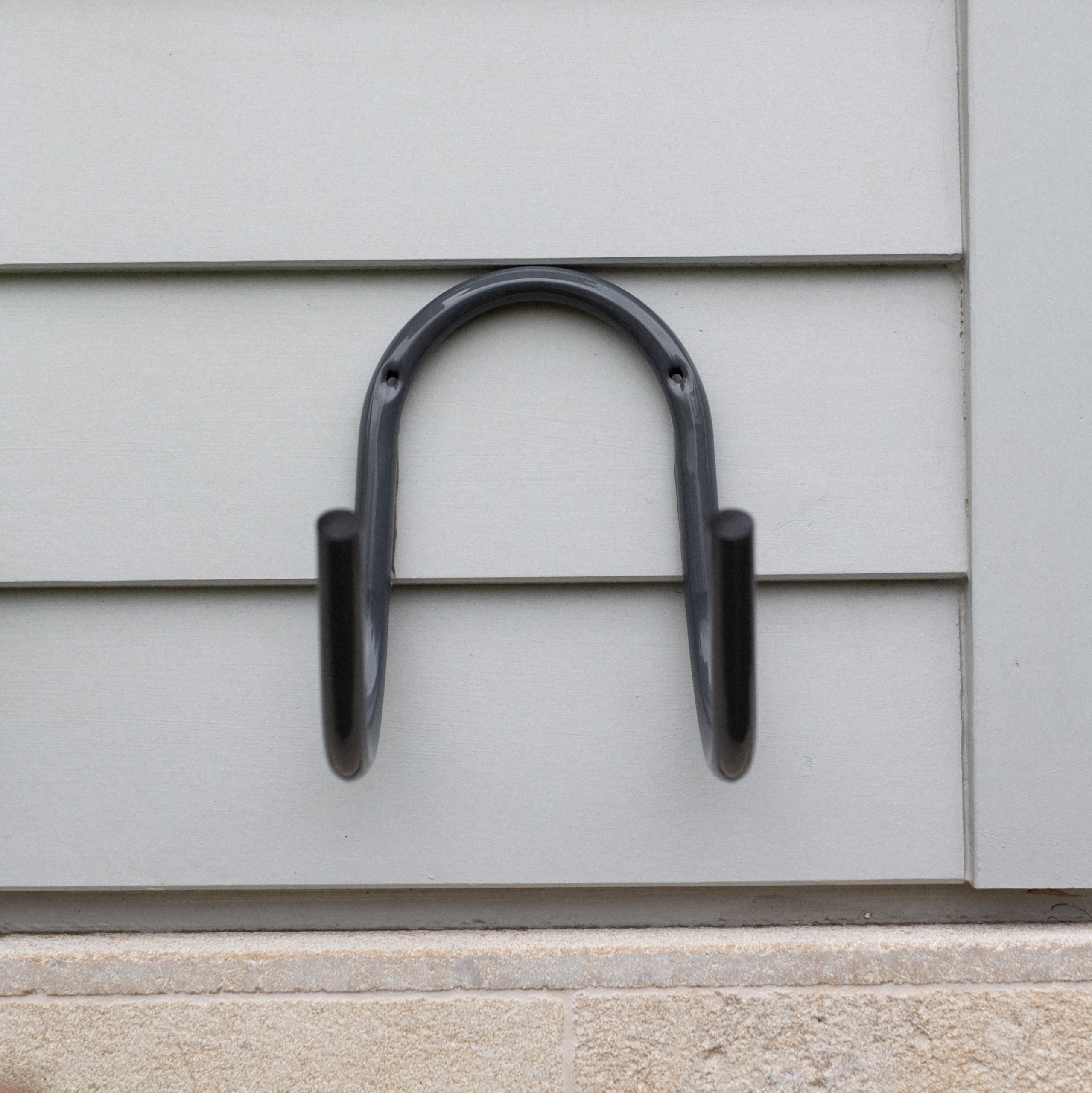 Store a loose garden hose neatly off the ground with the Hoselink Stainless Steel Hose Hanger. The wall-mounted curved support holds coiled hose securely and provides a durable